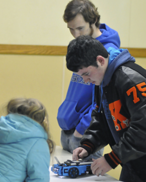 Keota junior Justin Hickman (right) inspects a TI-Innovator Rover while junior Trevor Doss looks on. Hickman is one of two students primarily responsible for programming the calculator that powers Rover to draw a robot.